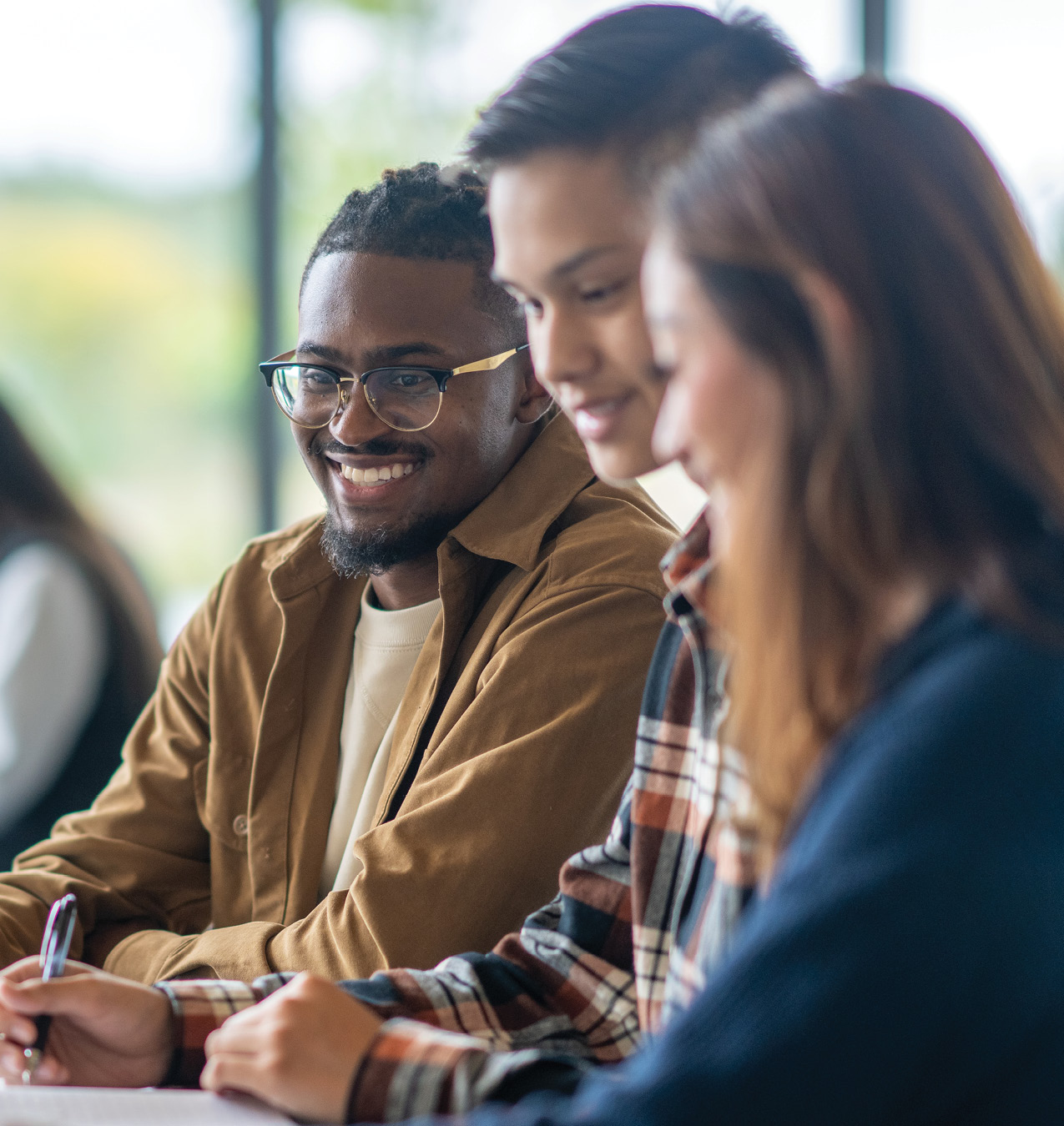 Stock image of three students studying: two young men and a young woman.