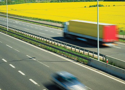 Semi truck, fuelled by canola-based biofuels, drives past a canola field in Canada.