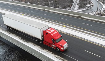 Red semi driving on Canadian highway, running on canola-based biofuel. 